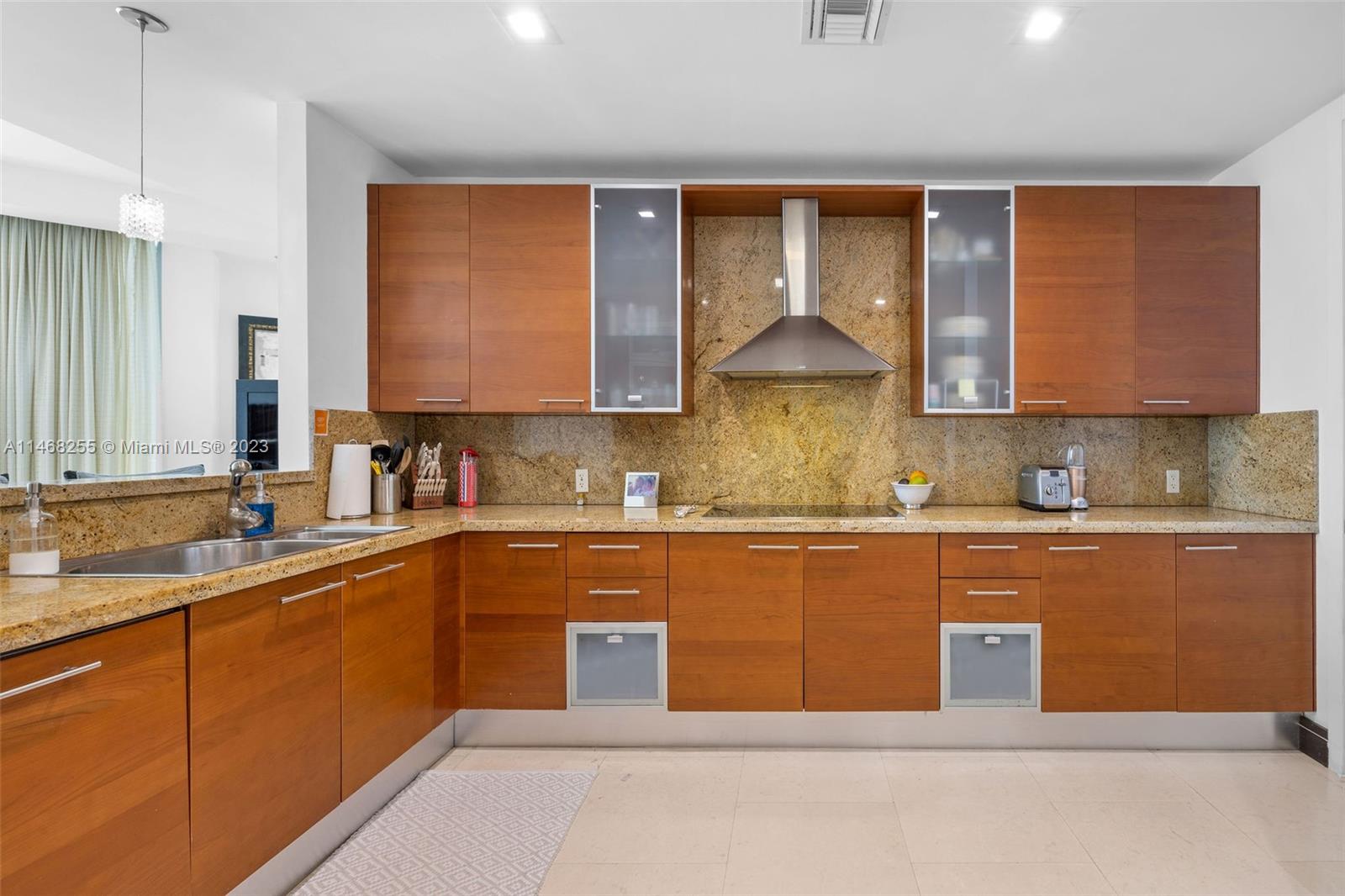5959 Collins Avenue, Unit 902 Miami Beach, FL 33140 - Photo 11 of 46 a kitchen with stainless steel appliances granite countertop a sink counter space cabinets and a large window