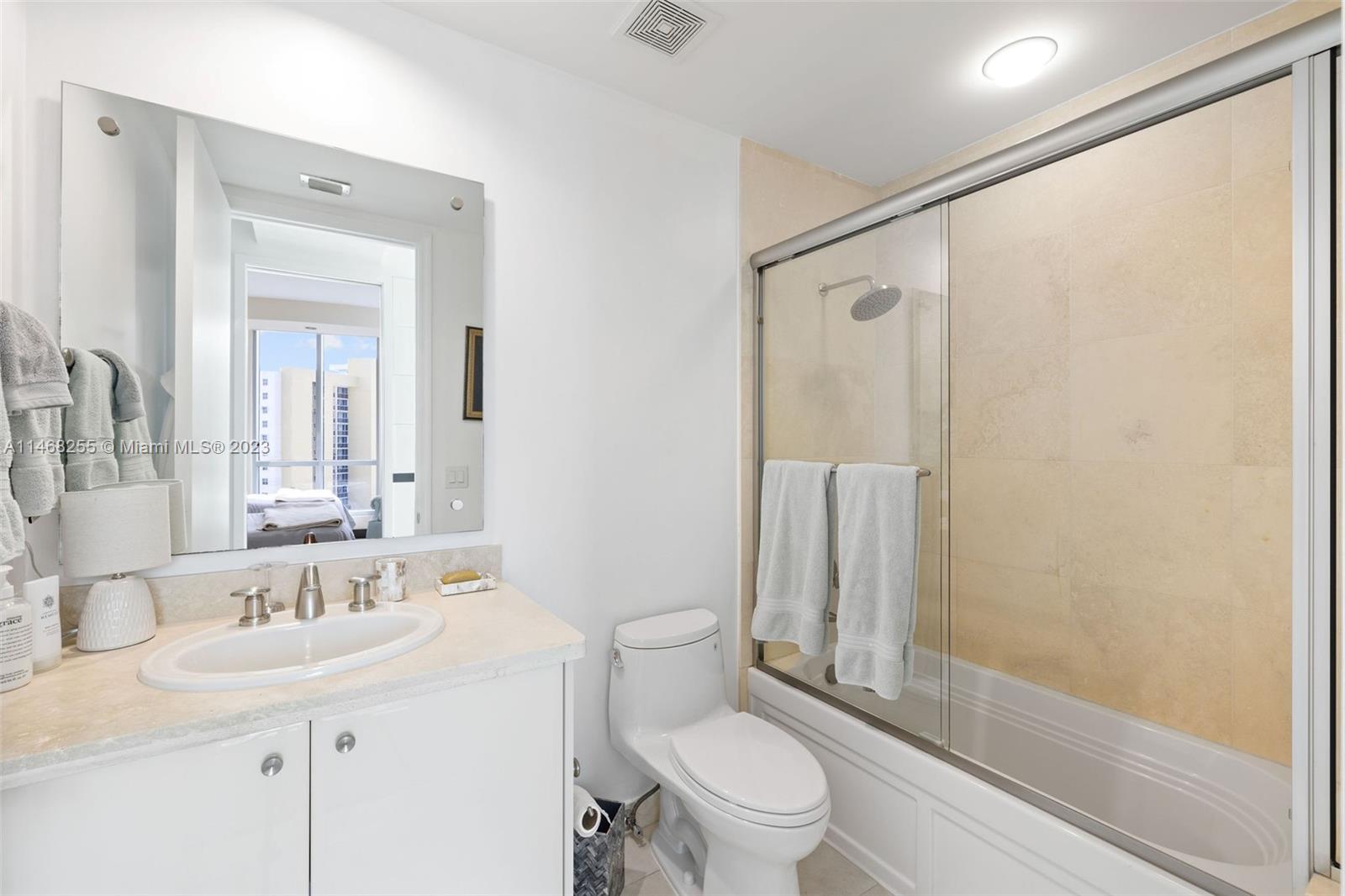 5959 Collins Avenue, Unit 902 Miami Beach, FL 33140 - Photo 28 of 46 a bathroom with a granite countertop sink toilet and shower