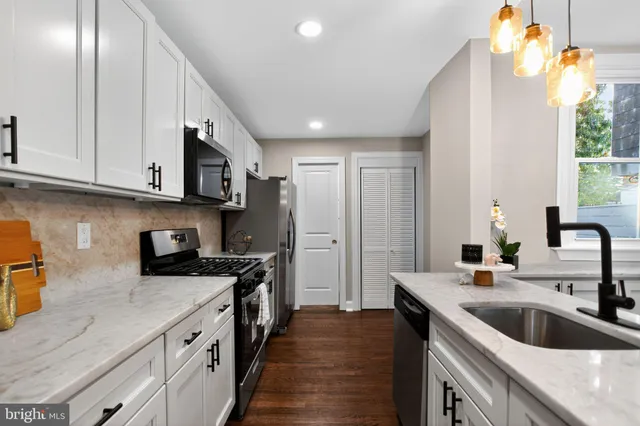 a kitchen with stainless steel appliances granite countertop a sink a stove and a refrigerator