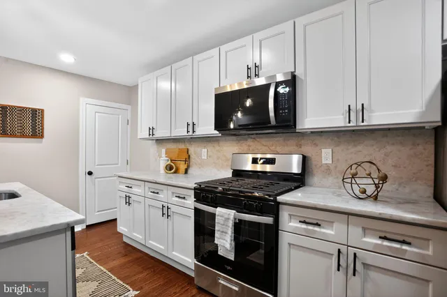 a kitchen with white cabinets and black appliances
