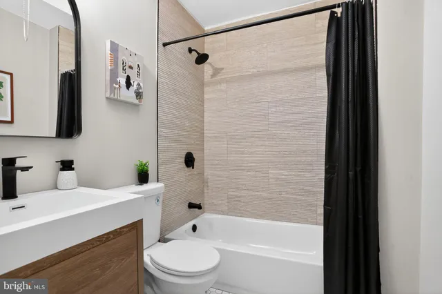 a bathroom with a bathtub shower sink vanity and toilet
