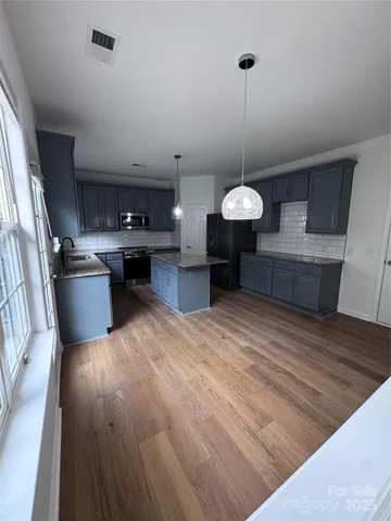 a kitchen with stainless steel appliances granite countertop a sink stove and wooden floor