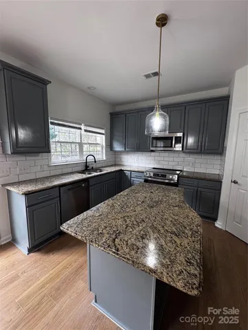 a kitchen with stainless steel appliances granite countertop a sink stove and wooden floor