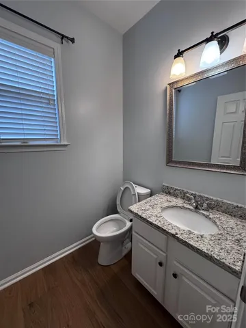 a bathroom with a granite countertop sink toilet and mirror