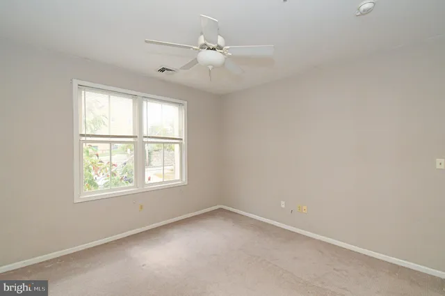 an empty room with windows and fan