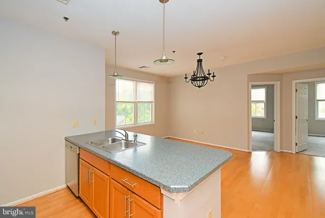 a view of a kitchen with a sink dishwasher a dining table and chairs with wooden floor