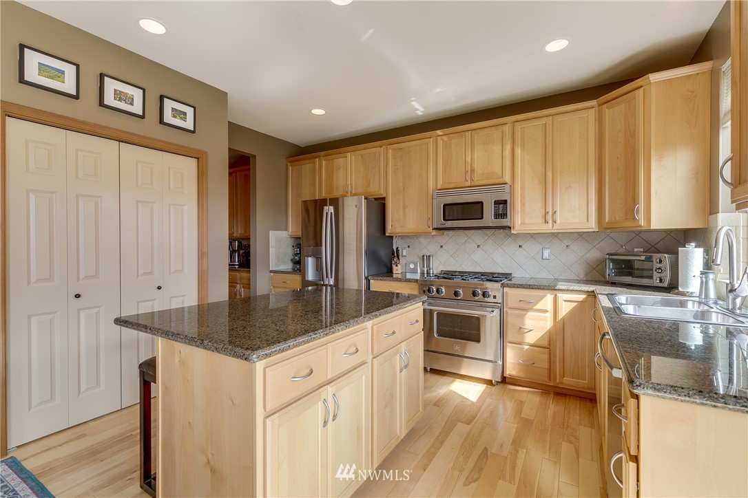 21105 1st Avenue West Bothell, WA 98021 - Photo 13 of 40 a kitchen with stainless steel appliances granite countertop a stove a sink and a refrigerator with wooden floors