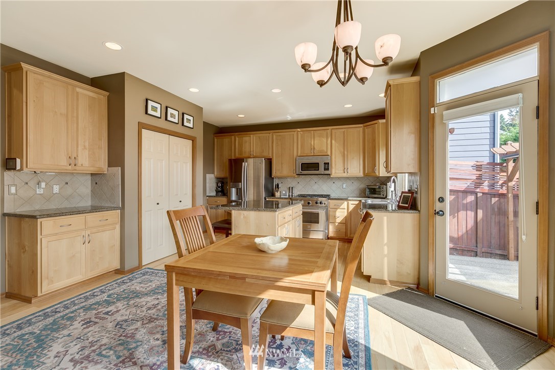 21105 1st Avenue West Bothell, WA 98021 - Photo 14 of 40 a kitchen with stainless steel appliances kitchen island granite countertop a refrigerator a stove top oven and a dining table with wooden floor