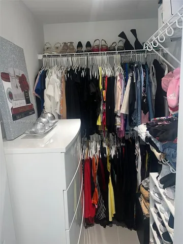 a view of walk in closet with clothes and shoes