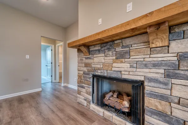 a view of an empty room with wooden floor fireplace and a window
