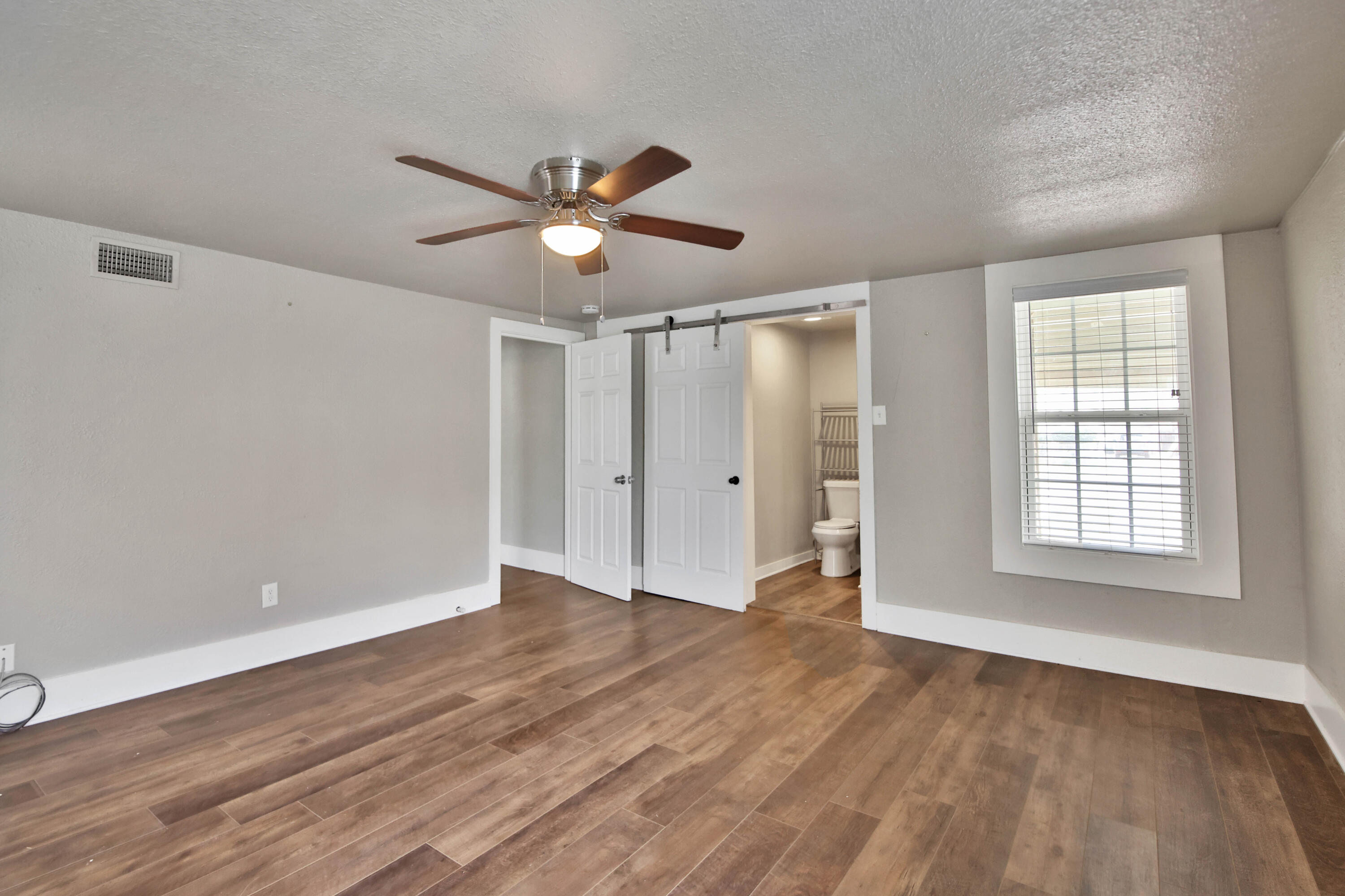 2408 24th Street Lubbock, TX 79411 - Photo 16 of 32 a view of an empty room with wooden floor and a window
