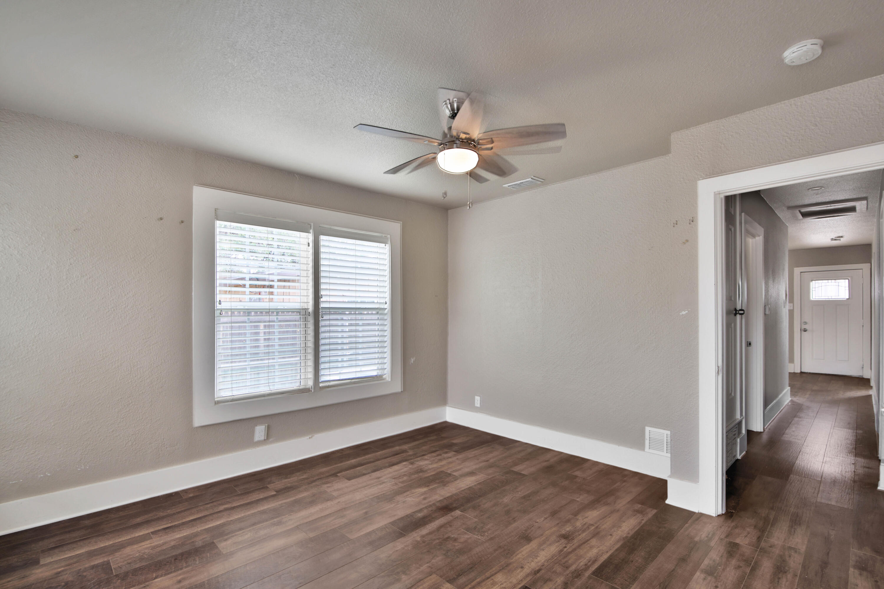 2408 24th Street Lubbock, TX 79411 - Photo 23 of 32 an empty room with wooden floor ceiling fan and windows