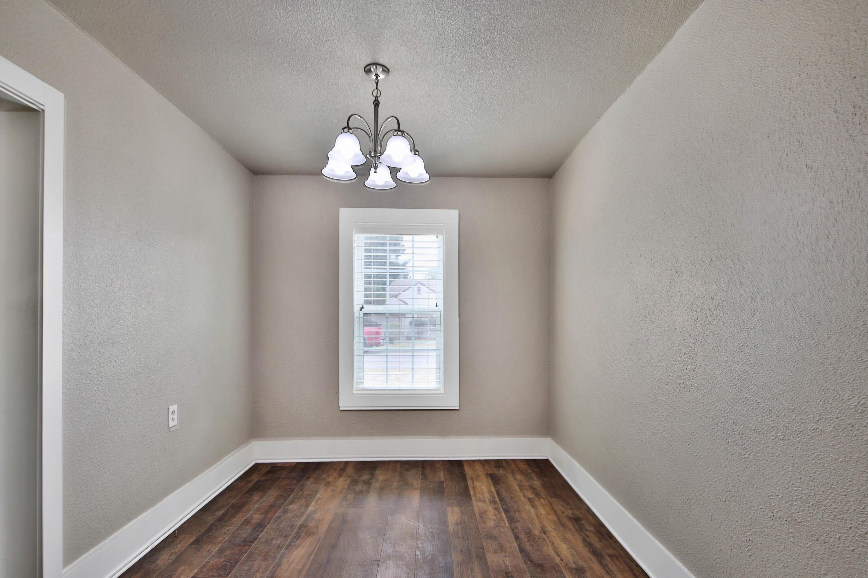 2408 24th Street Lubbock, TX 79411 - Photo 28 of 32 an empty room with wooden floor chandelier and window