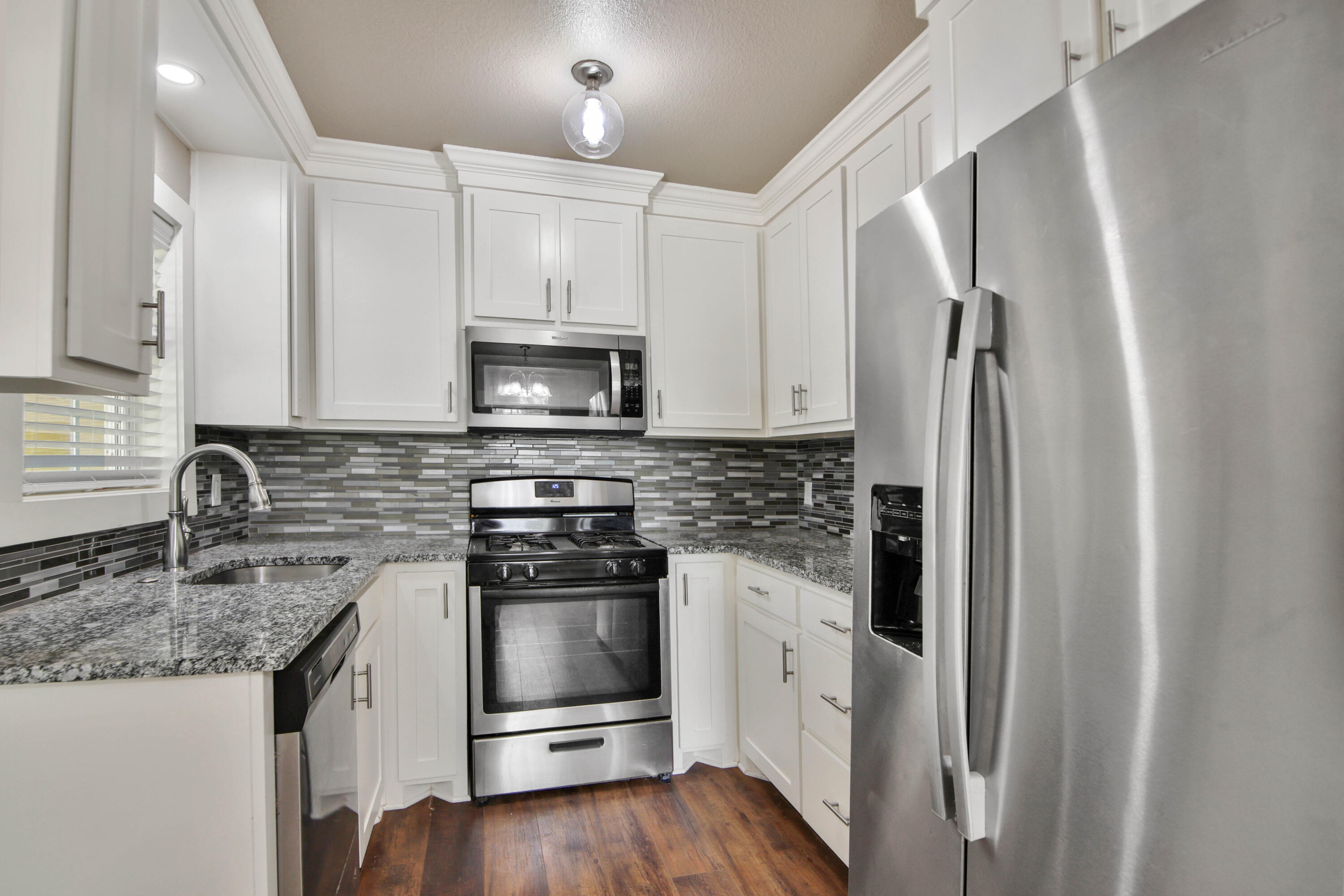 2408 24th Street Lubbock, TX 79411 - Photo 4 of 32 a kitchen with granite countertop a refrigerator stove and sink