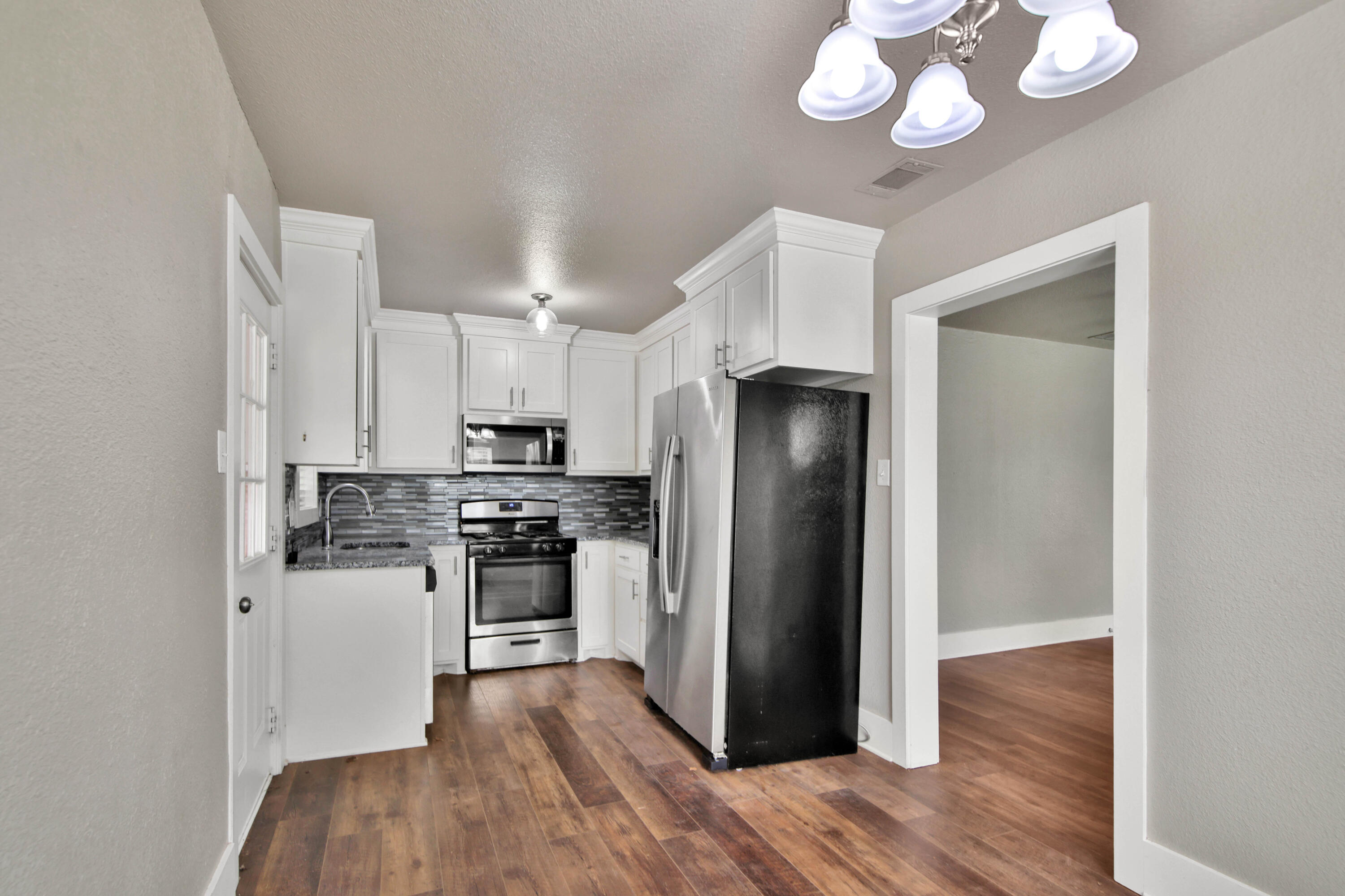 2408 24th Street Lubbock, TX 79411 - Photo 5 of 32 a kitchen with wooden floors and stainless steel appliances