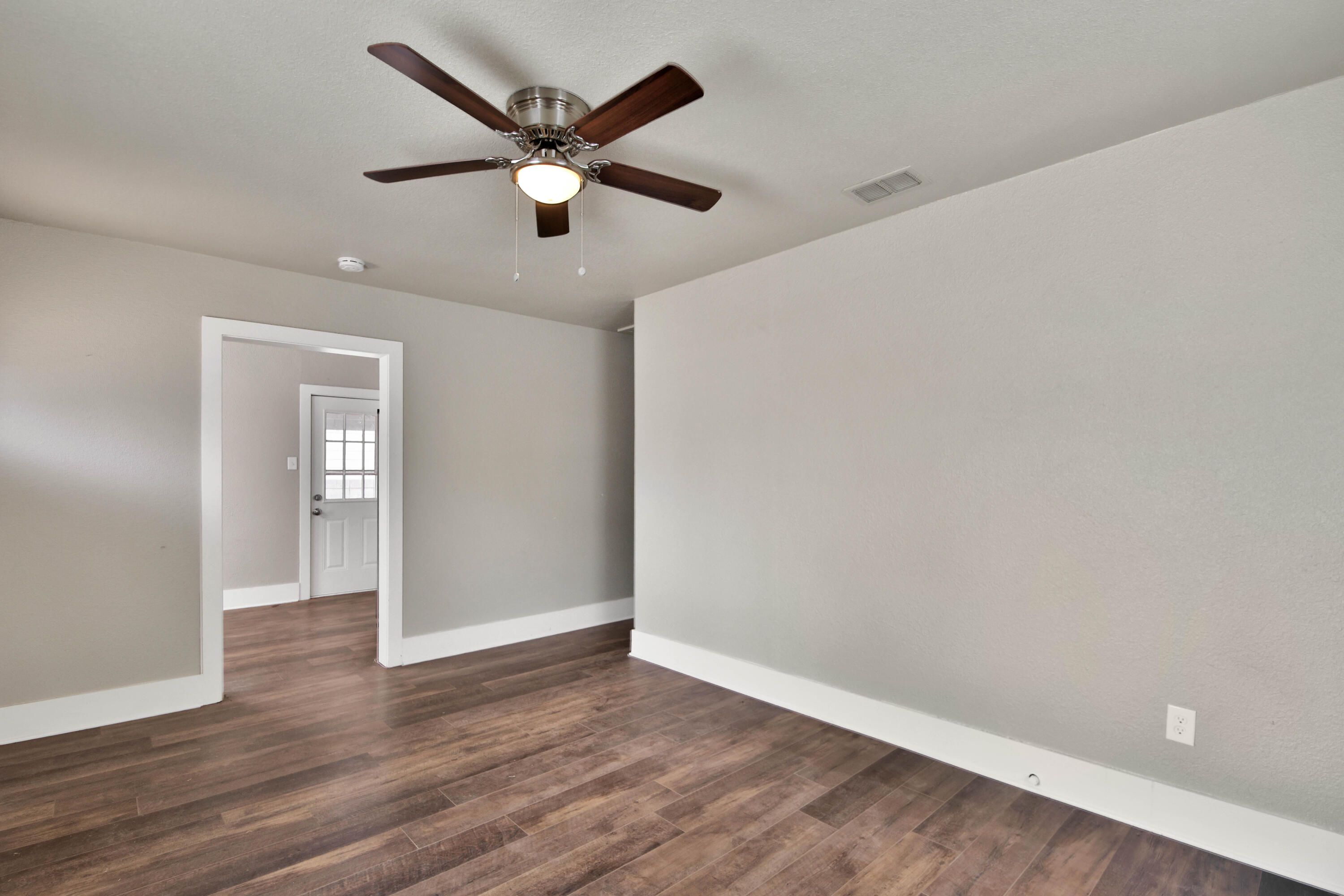 2408 24th Street Lubbock, TX 79411 - Photo 8 of 32 an empty room with wooden floor and a ceiling fan