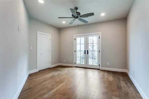 an empty room with wooden floor fan and windows