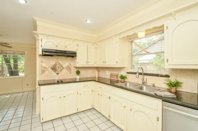 a kitchen with granite countertop a refrigerator sink and cabinets