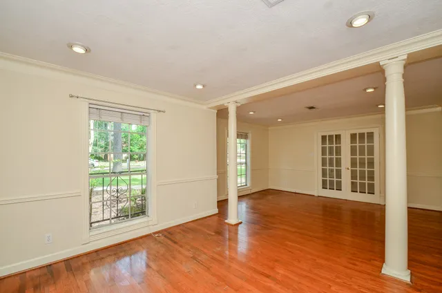 a view of an empty room with wooden floor and a window
