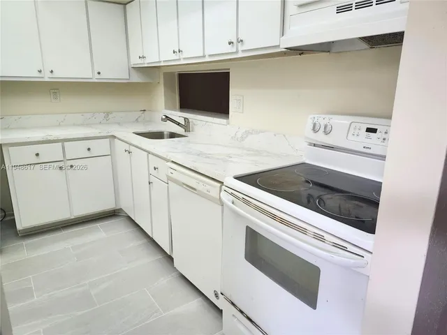 a kitchen with granite countertop white cabinets and white appliances