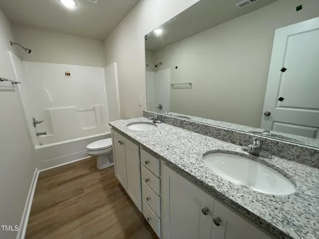 a bathroom with a granite countertop sink a toilet and shower