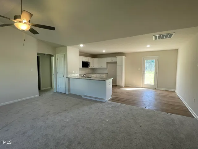 a view of an empty room with a kitchen