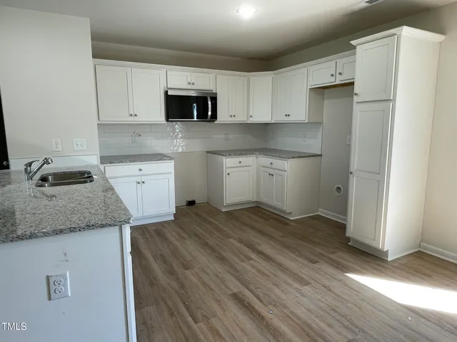 a kitchen with granite countertop a sink stove and refrigerator