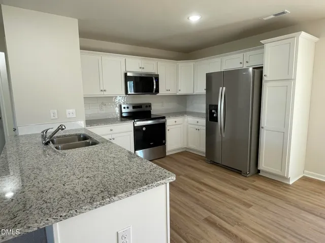 a kitchen with stainless steel appliances granite countertop a refrigerator a sink a stove a microwave and island