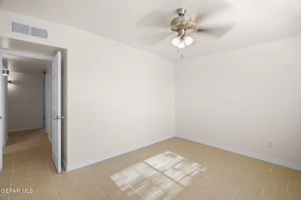 an empty room with a chandelier fan and windows