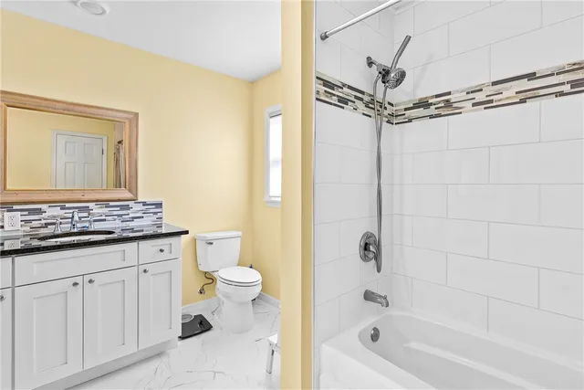 a bathroom with a granite countertop sink a toilet and shower