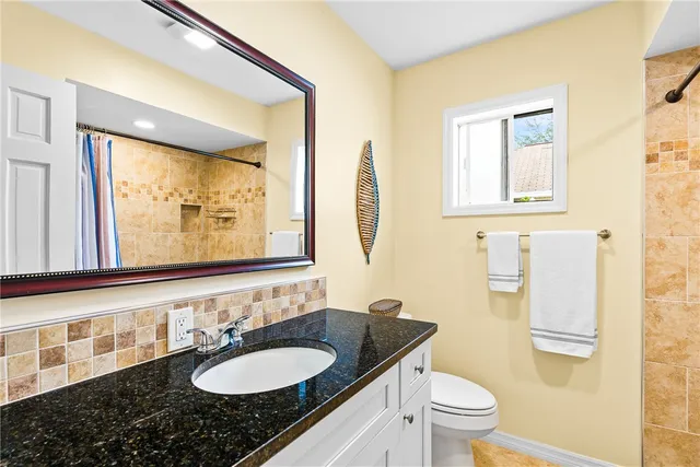 a bathroom with a granite countertop sink toilet and mirror