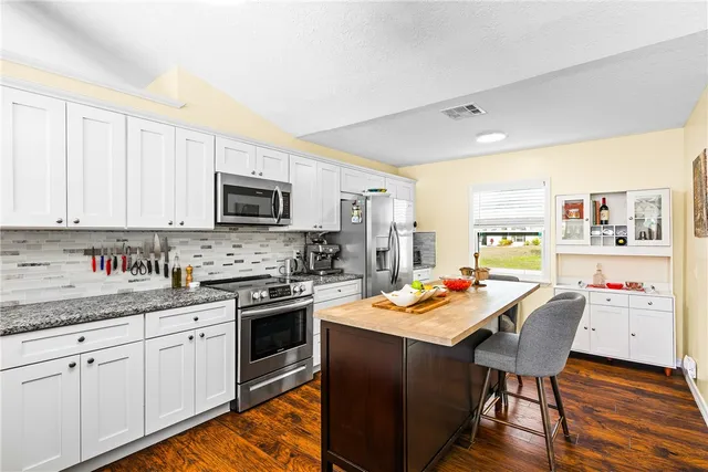 a kitchen with granite countertop stainless steel appliances a stove top oven a sink a counter space and cabinets