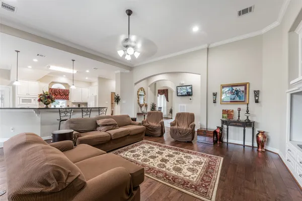 a living room with furniture kitchen view and a chandelier