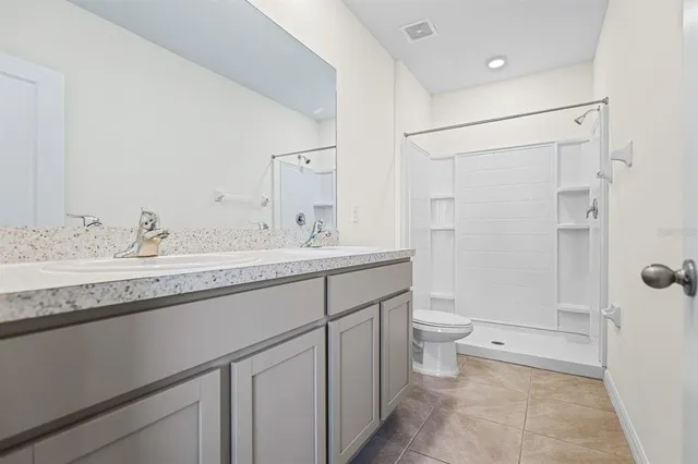 a bathroom with a granite countertop sink a toilet and shower