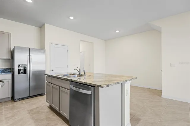 a kitchen with kitchen island granite countertop a sink stove and refrigerator