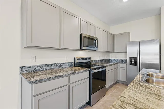a kitchen with kitchen island granite countertop a sink stove and refrigerator
