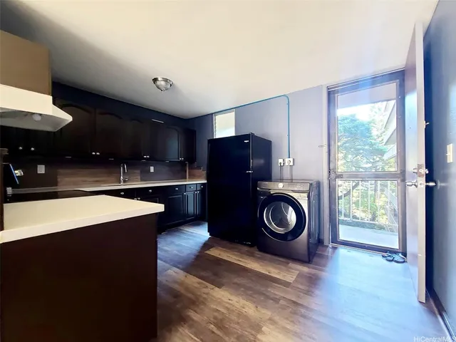 a view of a room with kitchen island stainless steel appliances wooden floor and window