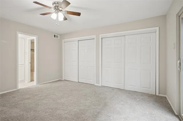 a view of an empty room and chandelier fan