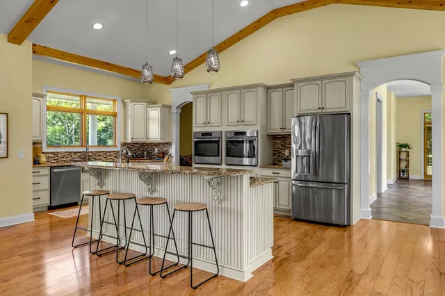 a kitchen with stainless steel appliances granite countertop a stove top oven a sink a refrigerator and white cabinets