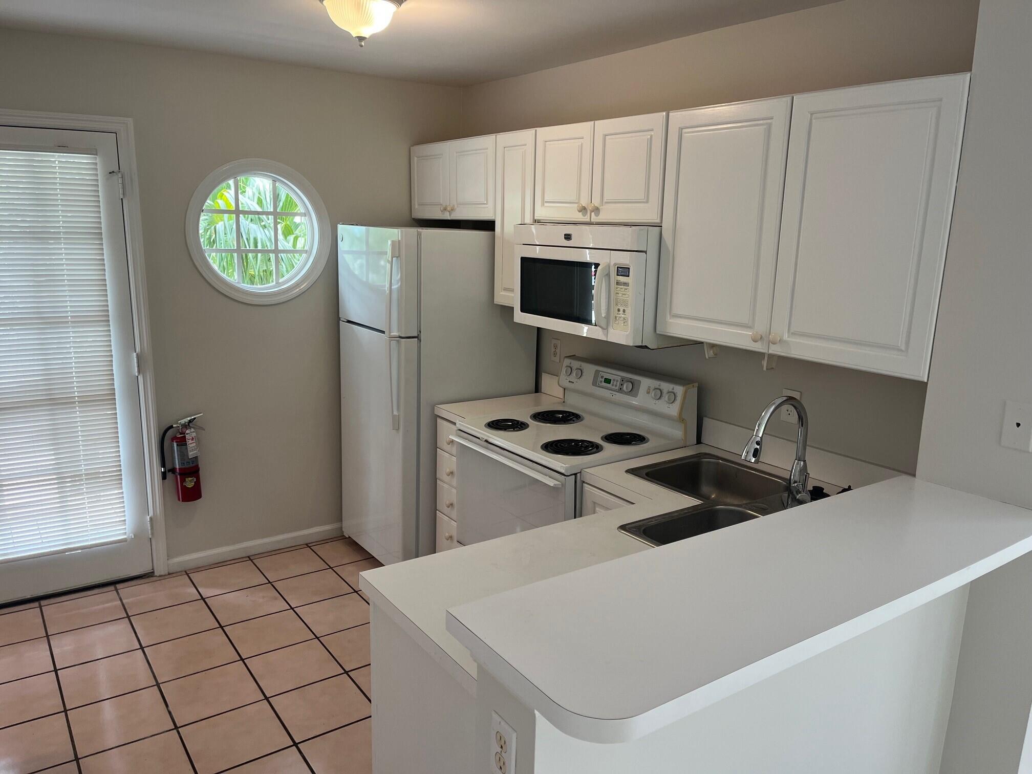 8 Kestral Way Key West, FL 33040 - Photo 3 of 4 a kitchen with a white stove a refrigerator a sink a microwave and cabinets