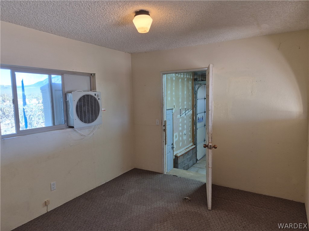 26432 Tamarisk Street, Unit STREET Meadview, AZ 86444 - Photo 10 of 60 Empty room featuring a textured ceiling and carpet floors with entry to the 20x40 garage.