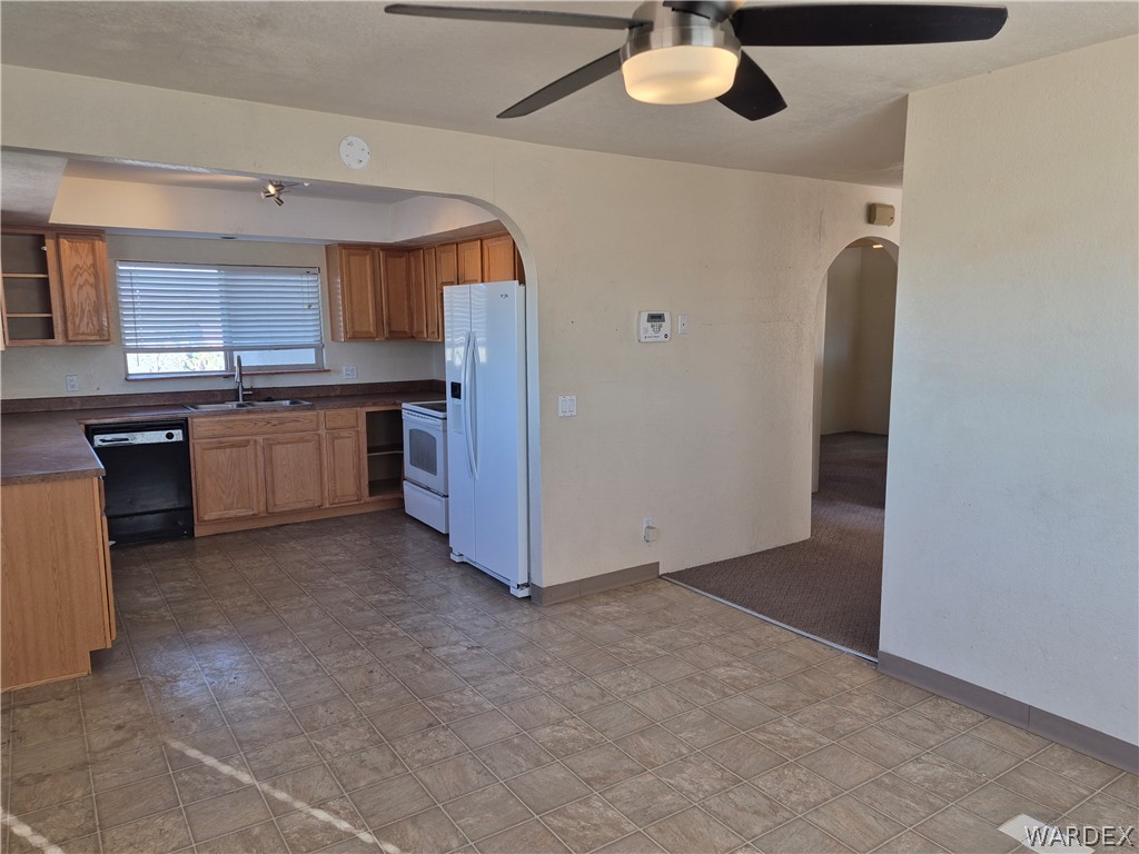 26432 Tamarisk Street, Unit STREET Meadview, AZ 86444 - Photo 13 of 60 Kitchen featuring open shelves, a ceiling fan, dark countertops, white appliances, and wood finish cabinets