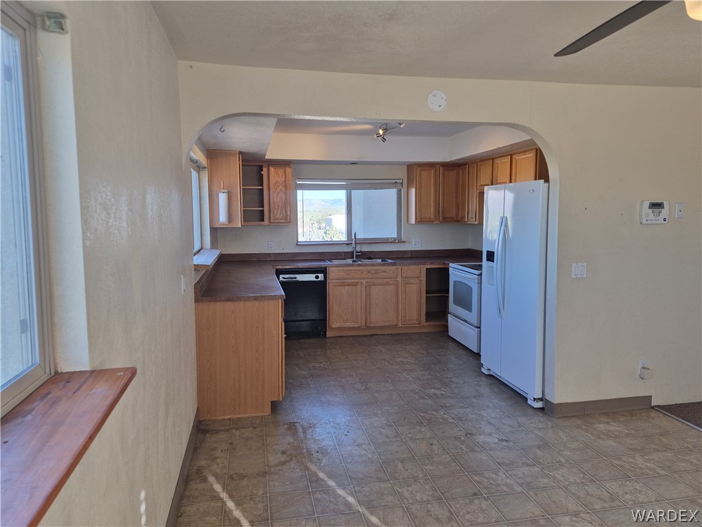 26432 Tamarisk Street, Unit STREET Meadview, AZ 86444 - Photo 17 of 60 Kitchen featuring white appliances, open shelves, dark countertops, wood finish cabinetry, and arched walkways