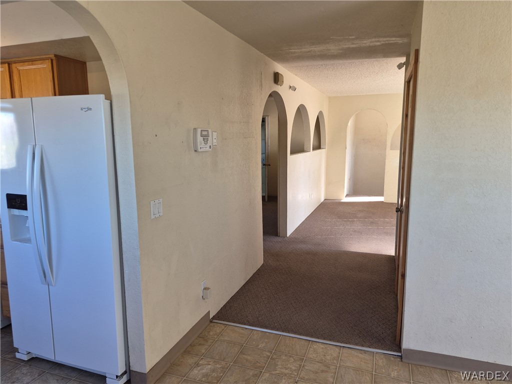 26432 Tamarisk Street, Unit STREET Meadview, AZ 86444 - Photo 18 of 60 Corridor with arched walkways, a textured wall, and light carpet