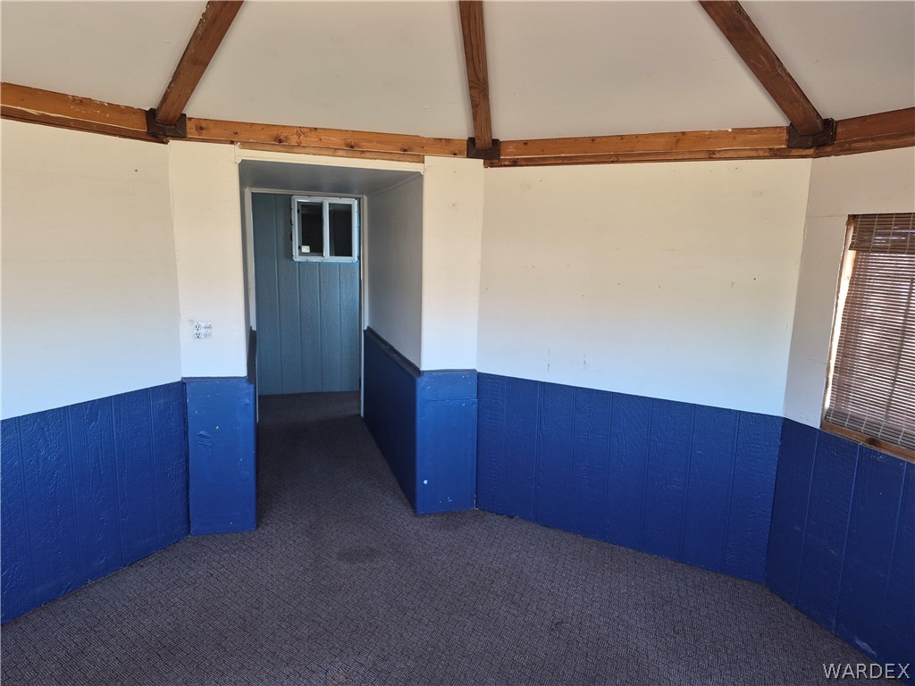 26432 Tamarisk Street, Unit STREET Meadview, AZ 86444 - Photo 23 of 60 Spare room with a wainscoted wall, dark carpet, wood walls, and vaulted ceiling with beams
