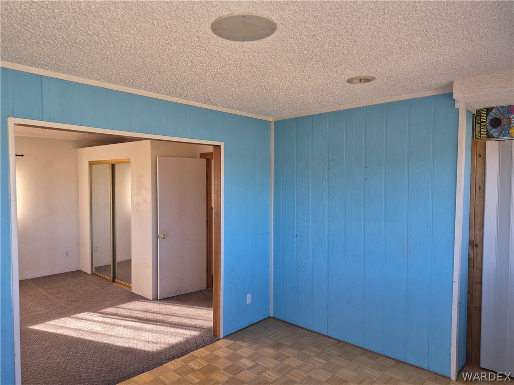 26432 Tamarisk Street, Unit STREET Meadview, AZ 86444 - Photo 32 of 60 Unfurnished bedroom featuring a closet, a textured ceiling, and crown molding