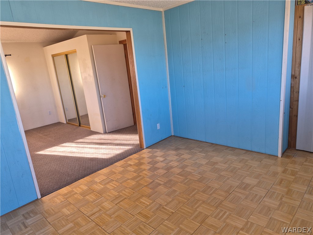 26432 Tamarisk Street, Unit STREET Meadview, AZ 86444 - Photo 33 of 60 Unfurnished bedroom featuring a closet, wooden walls, and a textured ceiling