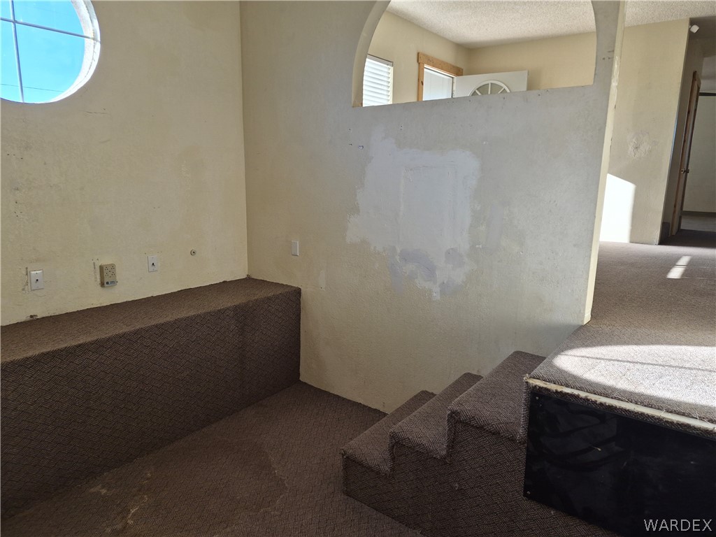 26432 Tamarisk Street, Unit STREET Meadview, AZ 86444 - Photo 5 of 60 Spare room featuring dark colored carpet, a textured ceiling, and rail lighting