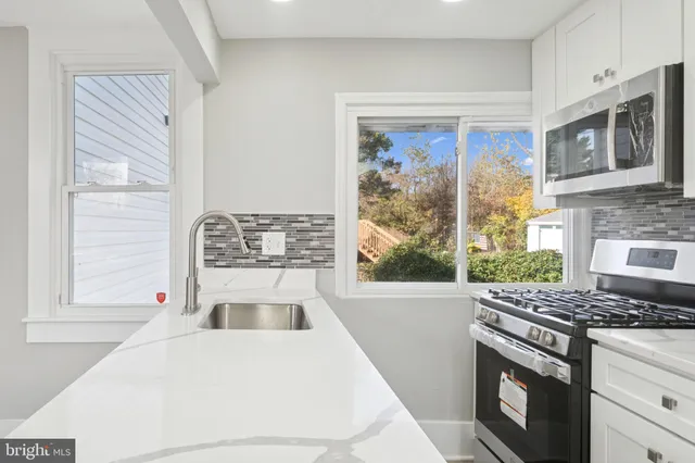 a kitchen with stainless steel appliances granite countertop a stove a sink and a microwave