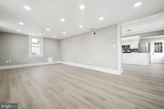 a view of a kitchen and an empty room with wooden floor